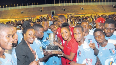 Carla Hollingworth of sponsor Gatorade (left) and Tahnida Nunes of co-sponsor Digicel (right) present the ISSA Manning Cup schoolboy trophy to St George’s College players after they defeated Hydel High 3-0 in the final at the National Stadium yesterday. (Photo: Marlon Reid)