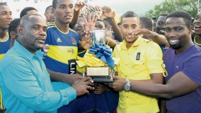 Dr Walton Small (left, foreground), president of ISSA; Stephen Miller (second right), of LIME; and Wisynco’s Jermaine Brown (right) present the ISSA/LIME Ben Francis KO trophy to Romario Thompson, captain of STETHS, after they beat Manchester High 2-0 in the final played at the STETHS Sports Complex yesterday.(PHOTO: PAUL REID)