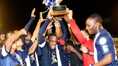 Jamaica's College's captain Junior Flemming (centre) lifts the ISSA/LIME Manning Cup trophy following his school's 3-2 extra-time victory over Wolmer's Boys in the final at the National Stadium yesterday. -Gladstone Taylor/Photgrapher
