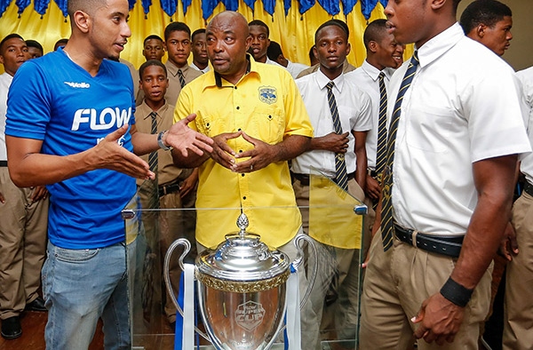 Stephen Miller, FLOW Sponsorship Manager ( left) discusses details of the 2015 ISSA/FLOW Super Cup Competition set to kick off on October 24 with Clarendon College coach Paul “Tegat” Davis (centre) and members of theCC Dacosta Cup team during the FLOW Super Cup Tour last Wednesday.
